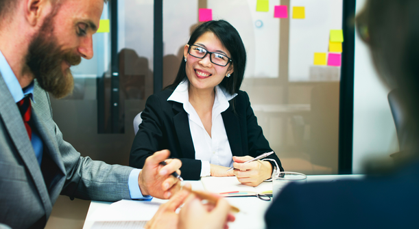 Photo of three people at desks in an office